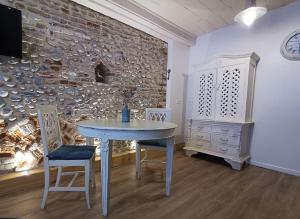 stół i krzesła w pokoju z kamienną ścianą w obiekcie Le macareux, maison de pêcheur. w mieście Saint-Valéry-sur-Somme