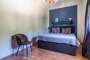 een slaapkamer met een bed en een stoel bij Villa Rose Garden in Panormos Skopelos