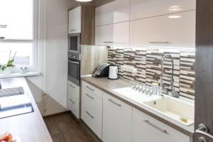 a kitchen with white cabinets and a sink at Sflower Apartman in Eger
