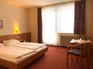 a bedroom with a bed and a desk and a window at Gästehaus Kaiserkrone in Schöna