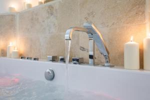 a bathroom with a bath tub with a faucet and candles at La loge de Sarah in Montpellier +8 photos