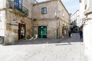 un antiguo edificio de piedra con una puerta verde en una calle en Turoqua Hostel, en Pontevedra