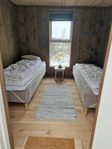 EikefjordにあるHoltarheim, holidayhouse, boat includedの窓とラグ付きの部屋のベッド2台