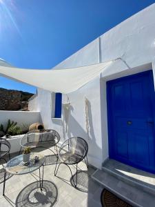 eine Terrasse mit Tischen und Stühlen und einer blauen Tür in der Unterkunft Cycladic Villa in Amorgos Island (Maison Shiro) in Arkesíni