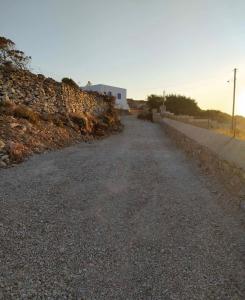 an empty road with a stone wall and a building at Cycladic Villa in Amorgos Island (Maison Shiro) in Arkesíni