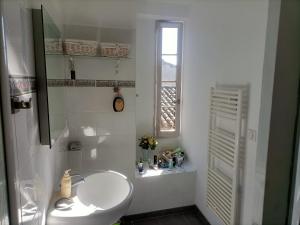 La salle de bains blanche est pourvue d'un lavabo et d'une fenêtre. dans l'établissement Maison paisible avec parking, à Montpezat-de-Quercy