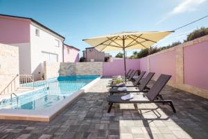 eine Terrasse mit Stühlen und einem Sonnenschirm neben einem Pool in der Unterkunft Apartman Laura in Vir