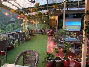 a patio with tables and chairs and plants and a television at The Panda in Dharamshala