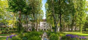 a garden in front of a building with trees and purple flowers at Les Albizias 5 in Eugénie-les-Bains