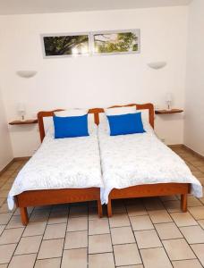 uma cama com almofadas azuis num quarto em Les Albizias 5 em Eugénie-les-Bains