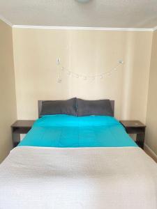 1 cama con manta azul y 2 mesitas de noche en Esperanza, en Los Andes