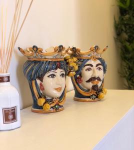 dois vasos com cabeças em coroas numa prateleira em Taormina Bedda Rooms em Taormina