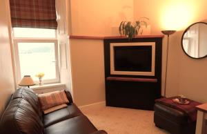 a living room with a couch and a television at An Cuilidh in Port Bannatyne