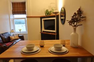 a wooden table with two cups and a vase on it at An Cuilidh in Port Bannatyne