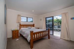 een slaapkamer met een bed en een groot raam bij Hosts on the Coast Peaceful Dotterel in Whitianga