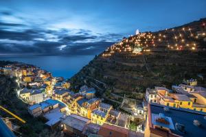 een stad aan de zijkant van een heuvel 's nachts bij Cà du Nilo in Manarola