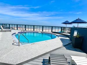a swimming pool on a deck next to the ocean at Absolute Beach - Sea View at Symphony Beach Club! in Ormond Beach
