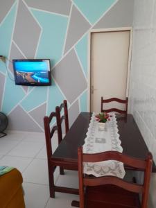 mesa con 2 sillas y TV en la pared en Cantinho da Bethânia en São Pedro da Aldeia