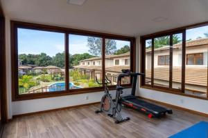 einen Fitnessraum mit Laufband und großen Fenstern in der Unterkunft Apartamento na Vila de Barra Grande - Bahia in Barra Grande