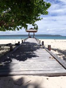 einen Holzweg, der zu einem Pavillon am Strand führt in der Unterkunft Home Stay Ramli in Bira