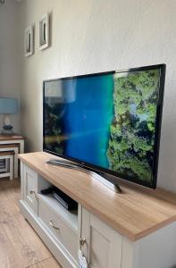 duży telewizor z płaskim ekranem siedzący na szafce w obiekcie Dunes View - Atlantic Bay w mieście Perranporth