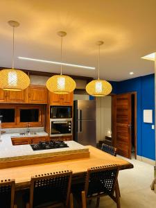 a kitchen with a wooden table with chairs and lights at Bali BG Casa Bamboo in Barra Grande
