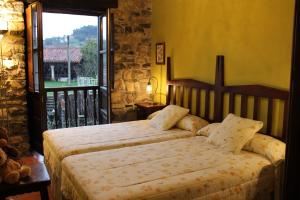 a bedroom with two beds and a large window at Rodiles Rural Apartamentos in Selorio
