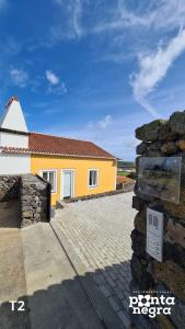 a yellow house with a stone wall in front of it at Casa das Lajes in Caldeira
