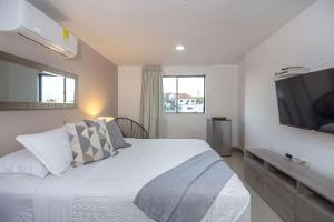 a bedroom with a white bed with a tv on the wall at Bahari Cartagena Suites in Cartagena de Indias