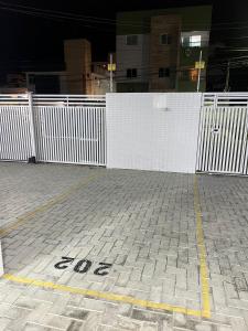 a parking lot with a white fence and a brick road at Aconchego Familiar in João Pessoa