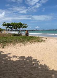 a sandy beach with a tree and the ocean at Aconchego Familiar in João Pessoa