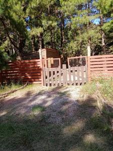 una cerca blanca frente a una valla de madera en Cabaña en el bosque de punta del diablo, en Punta del Diablo