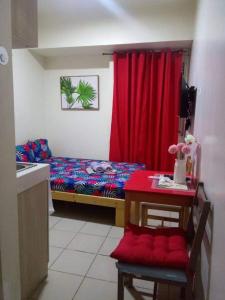 Cette petite chambre comprend un lit et un rideau rouge. dans l'établissement Urban Deca Tower @ Graceysplace Unit 4 Mandaluyong, à Manille