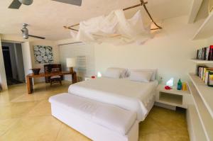 a bedroom with a white bed and a desk at Villa Los Cocos Baru in Barú