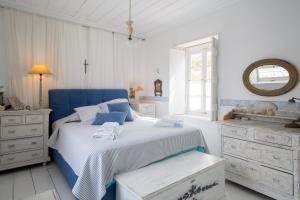 Dormitorio azul y blanco con cama y ventana en Lady of Hydra Villa, sea front view, private beach, en Hydra