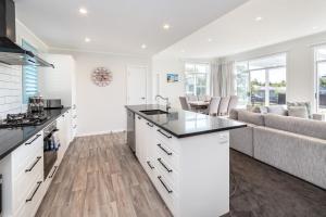 a kitchen with white cabinets and a living room with a couch at Blue Bungalow in Martinborough 