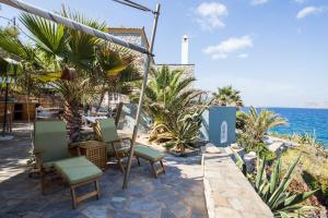 a patio with chairs and the ocean in the background at Lady of Hydra Villa, sea front view, private beach in Hydra