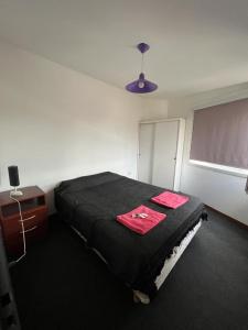 1 dormitorio con cama negra y pizarra en Alojamiento ruta 3 en Trelew