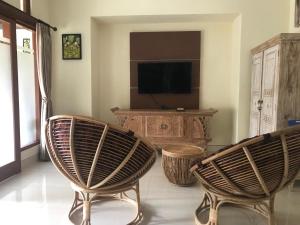 a living room with two chairs and a television at Bali Breeze Bungalows in Ubud