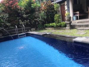 a pool with blue water in front of a house at Bali Breeze Bungalows in Ubud