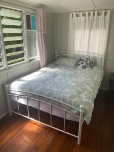 a bed sitting in a room with a window at Original Surf Cottage in heart of Pottsville Beach in Pottsville