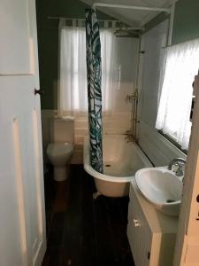 a bathroom with a tub and a toilet and a sink at Original Surf Cottage in heart of Pottsville Beach in Pottsville