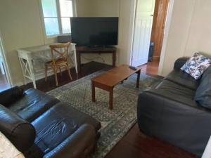 a living room with a leather couch and a coffee table at Original Surf Cottage in heart of Pottsville Beach in Pottsville