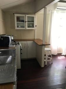 a kitchen with white cabinets and a counter top at Original Surf Cottage in heart of Pottsville Beach in Pottsville +8 photos