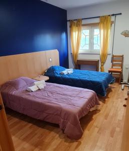Duas camas num quarto com paredes azuis em Vivenda do relaxo em Freiria