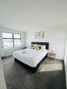 a white bedroom with a large bed and a window at Home sweet home Christchurch Centre in Christchurch