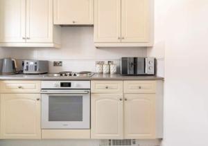 a kitchen with white appliances and white cabinets at Peniel Properties - Welwyn Garden City in Welwyn Garden City