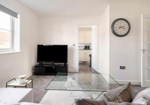 uma sala de estar com televisão e um relógio na parede em Peniel Properties - Welwyn Garden City em Welwyn Garden City