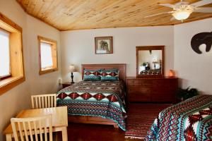 1 dormitorio con 2 camas, mesa y espejo en Red Moon Lodge en Moab