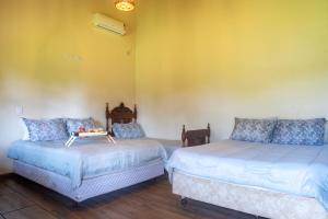two beds in a room with yellow walls at Recanto do sossego!! in Morretes